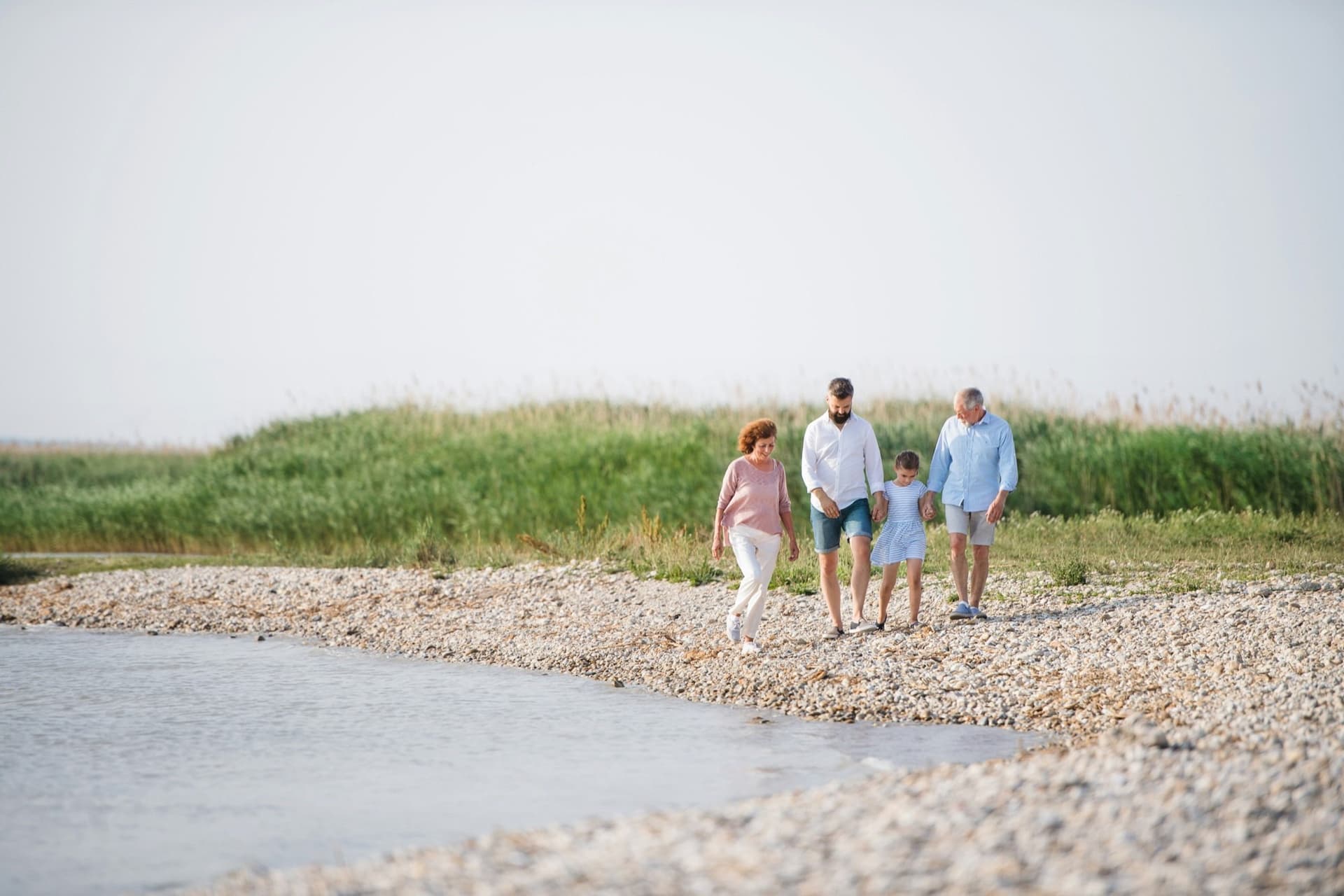 Three generations of a family walking together along a pebble shoreline