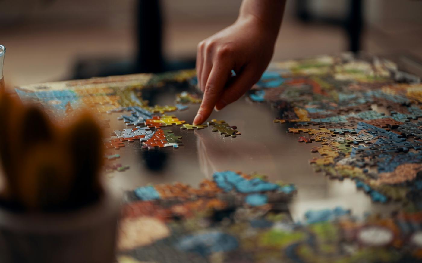 person holding jigsaw puzzle piece by Ross Sneddon courtesy of Unsplash.