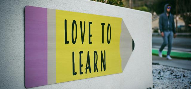 love to learn pencil signage on wall near walking man by Tim Mossholder courtesy of Unsplash.