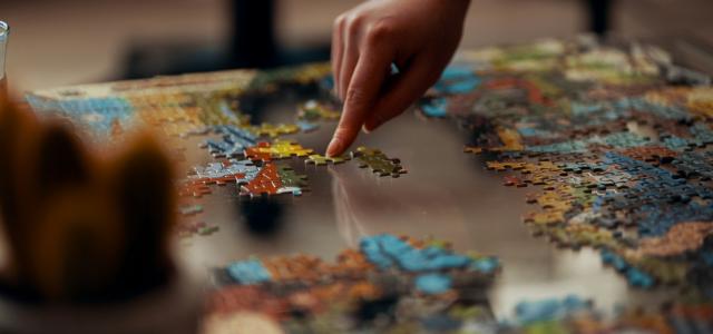 person holding jigsaw puzzle piece by Ross Sneddon courtesy of Unsplash.